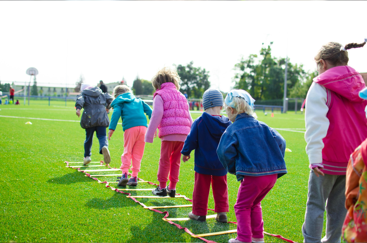 Mehrere Kinder, die auf einem Sportplatz in gelegte Quasrate springen.